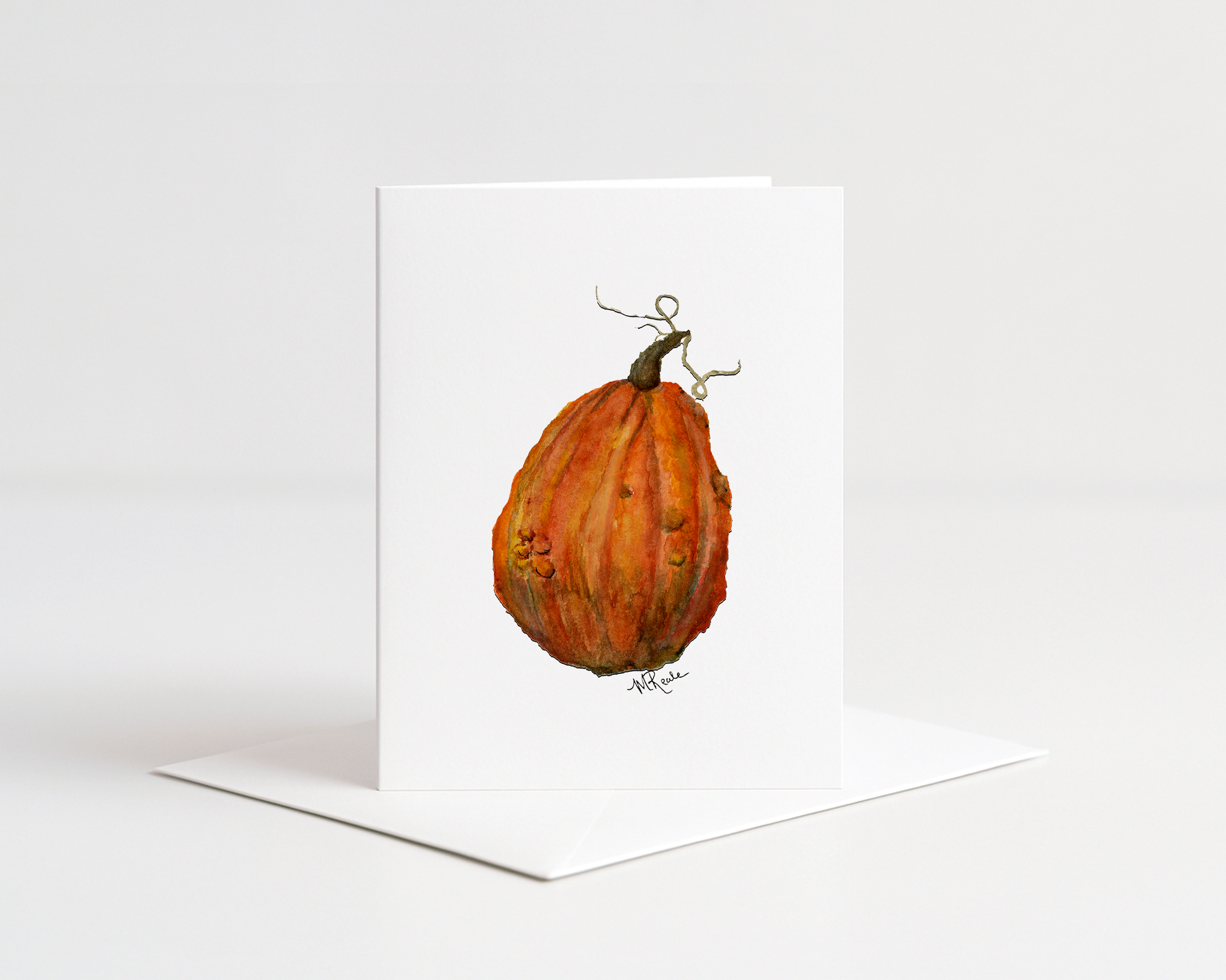 Handmade greeting card featuring a watercolor painting of an orange pumpkin with a brown stem and curly tendrils, signed by the artist.