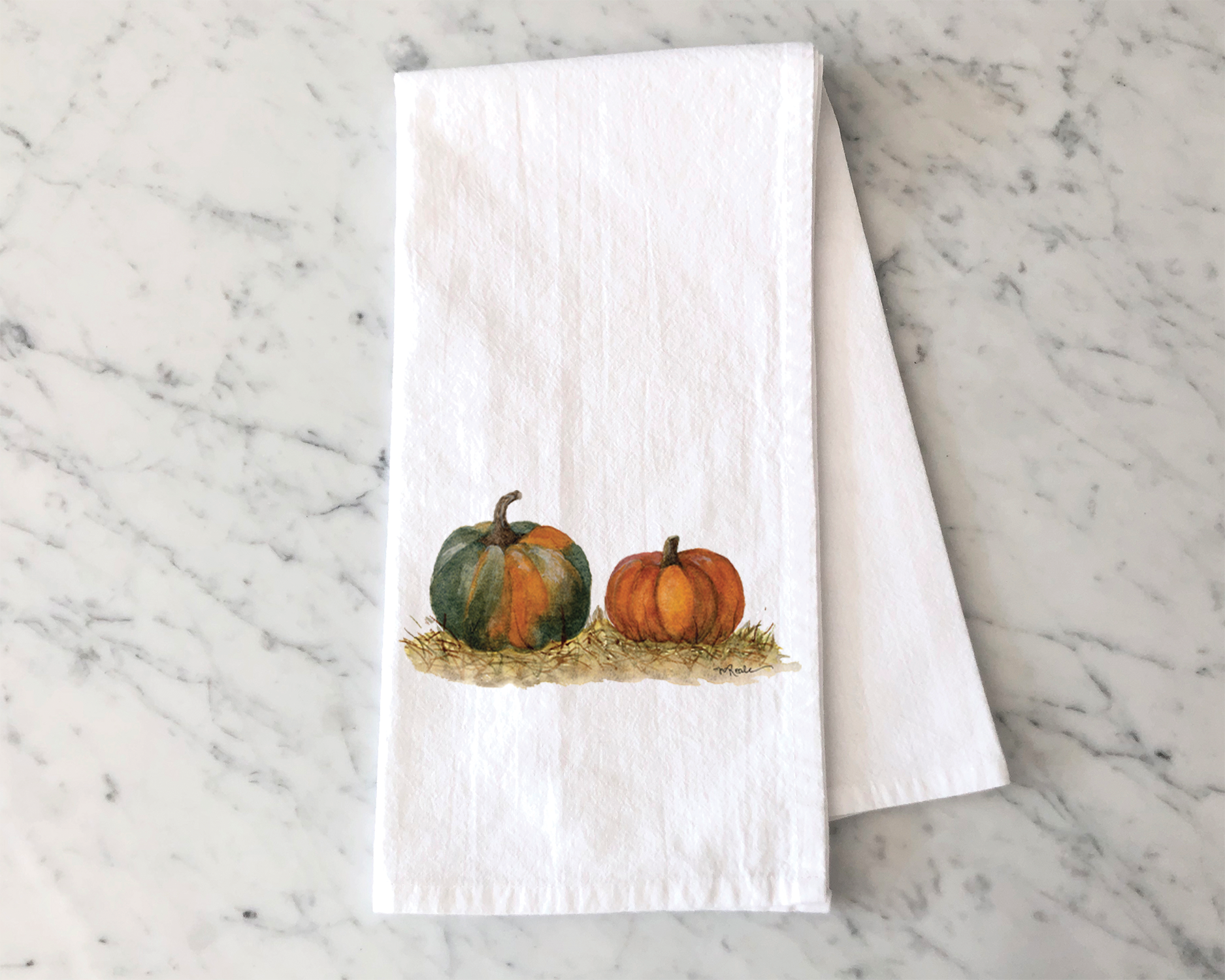 A decorated paper napkin with an illustration of three pumpkins, two small and one large, in autumn colors on a white, marbled surface.