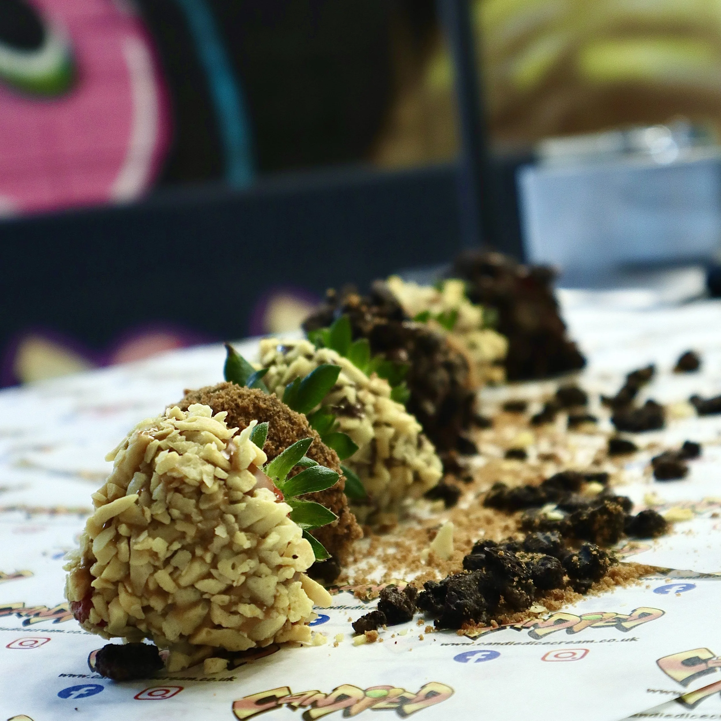 Assorted strawberries covered in chocolate and garnishes on a lined tray
