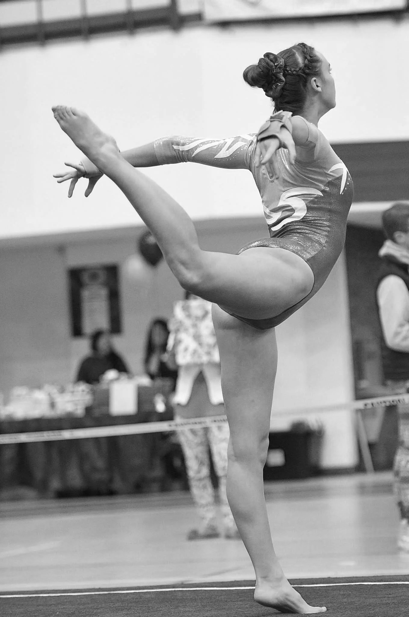 A female gymnast performing a balanced pose during a gymnastics competition.