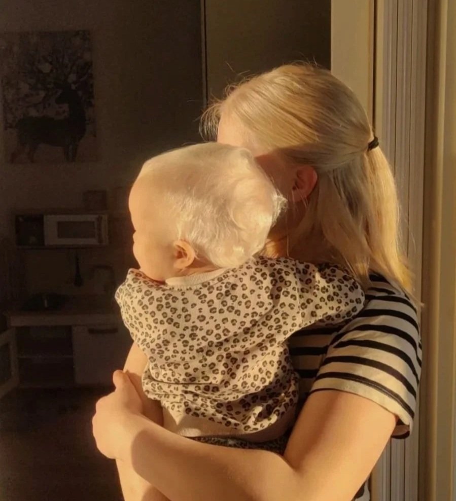 Lapsi äidin sylissä, lapsiperhe, vanhemmuus, lastenhuone, kotona.