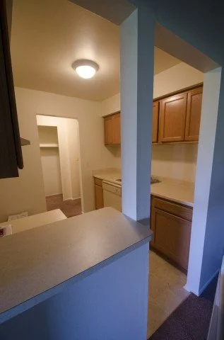 Kitchen with wooden cabinets and a partial view of a counter and hallway