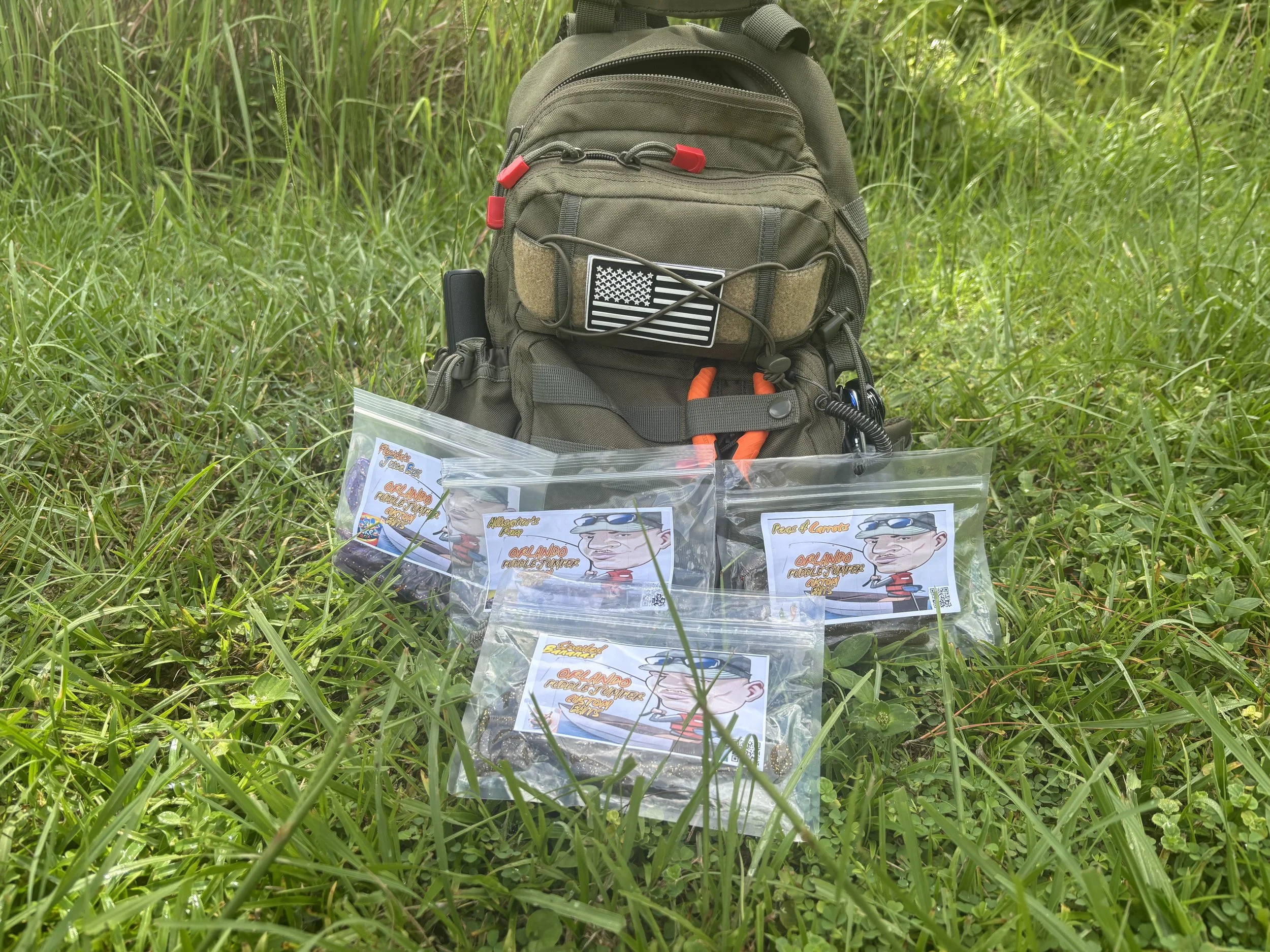 Backpack and four sealed plastic bags with labels, placed on grass in a natural outdoor setting.