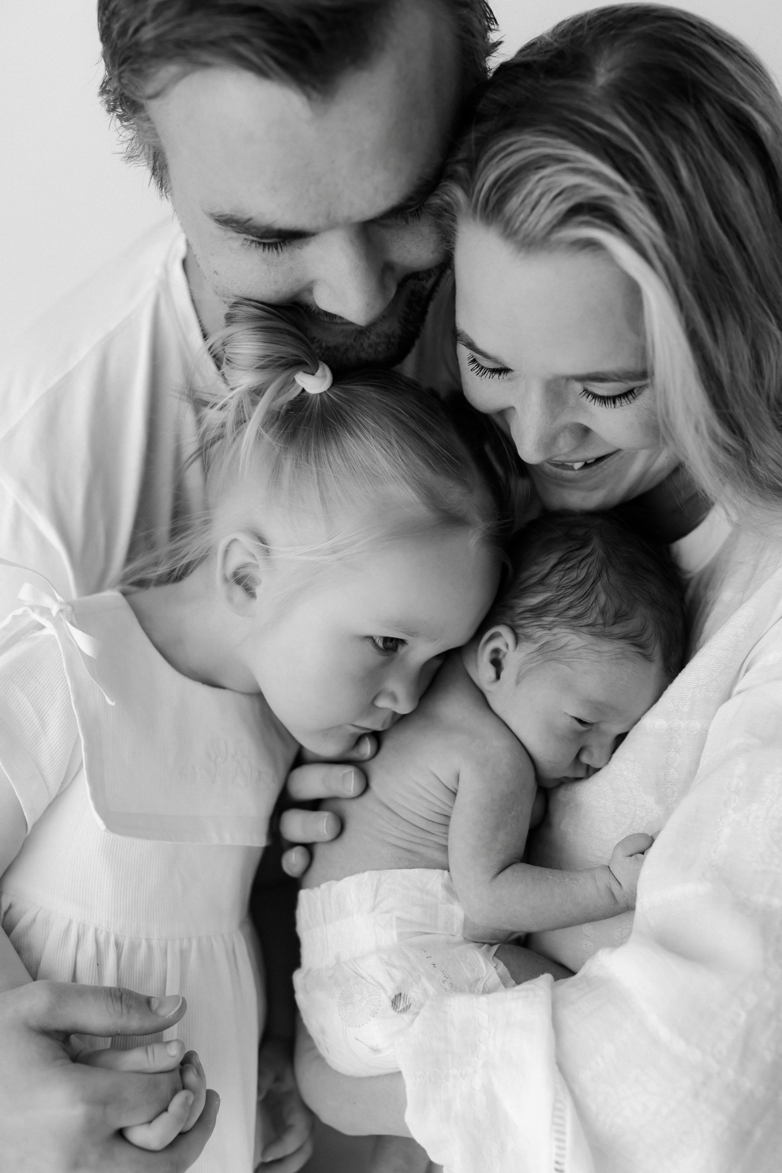 Black and white photograph of a family, including a father, mother, and three children, embracing and bonding closely.