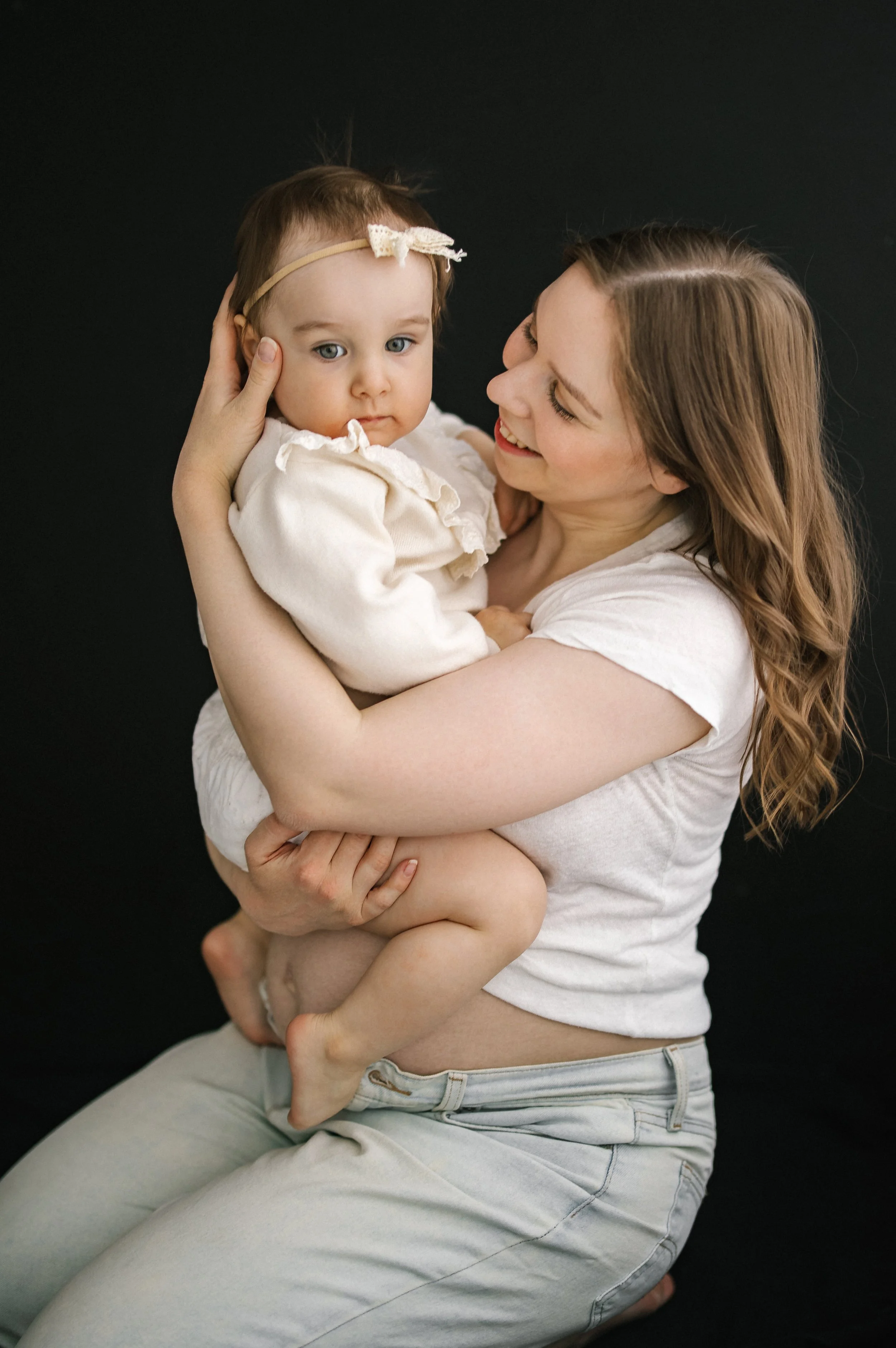A woman holding a young child against a black background