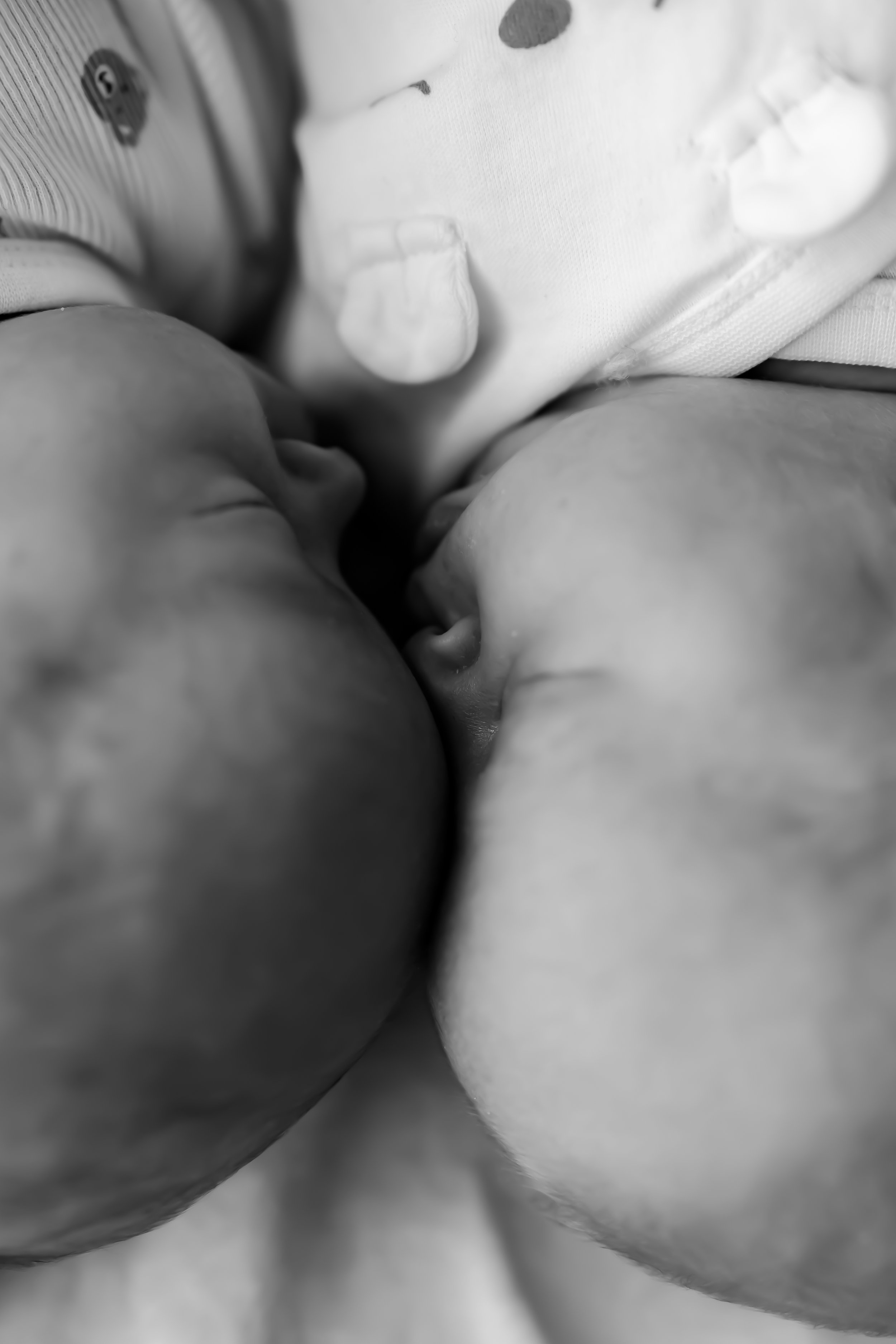 Close-up of a mother and baby's noses and foreheads touching, with the baby wearing a patterned outfit.