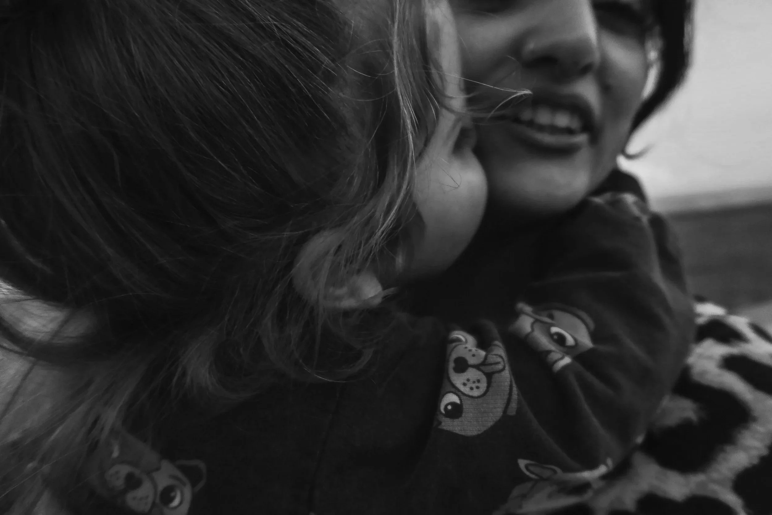 A woman and a young child are close together, sharing a moment of affection, with the woman smiling and the child's face partially turned.