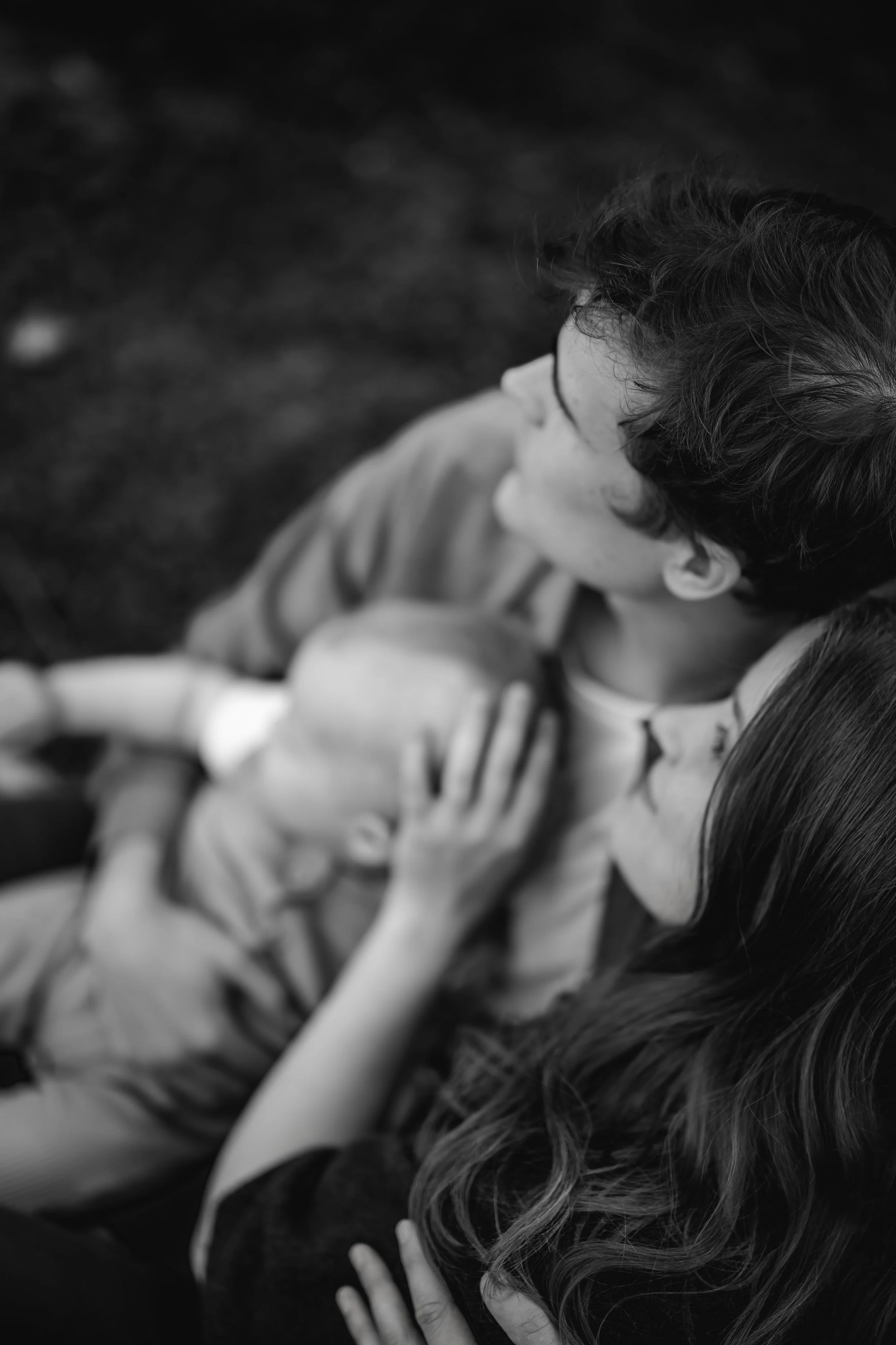 A woman holding a young boy on her lap and a baby in her arms, seen from above in black and white.
