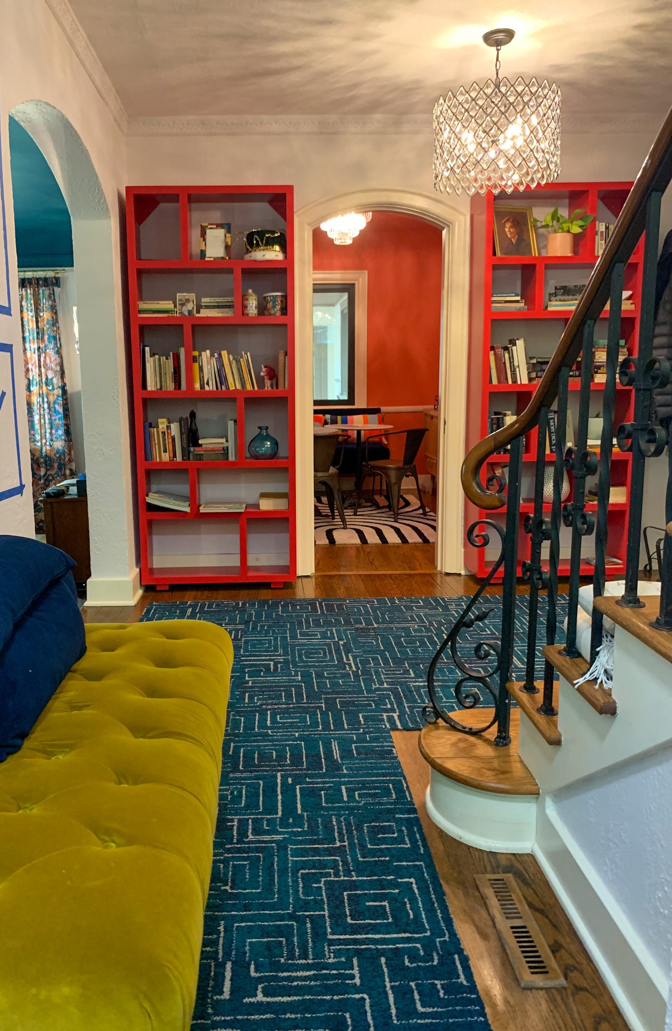 Colorful interior with bold red built-in bookshelves, patterned carpet in entryway
