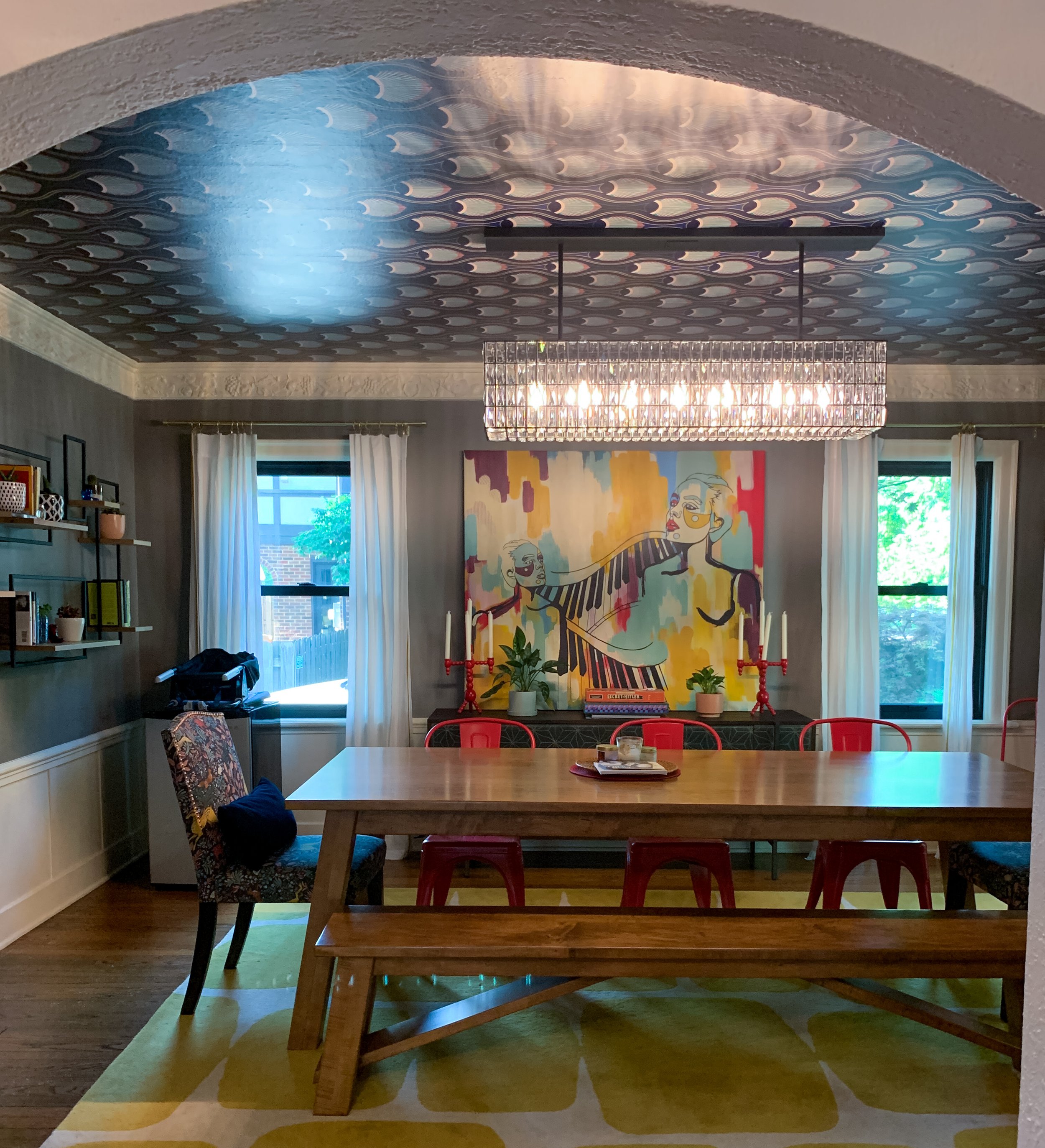Eclectic dining room with bold colorful music artwork, crystal chandelier, red chairs, and layered vintage-modern styling in Kansas City home by Melissa B. Rodgers