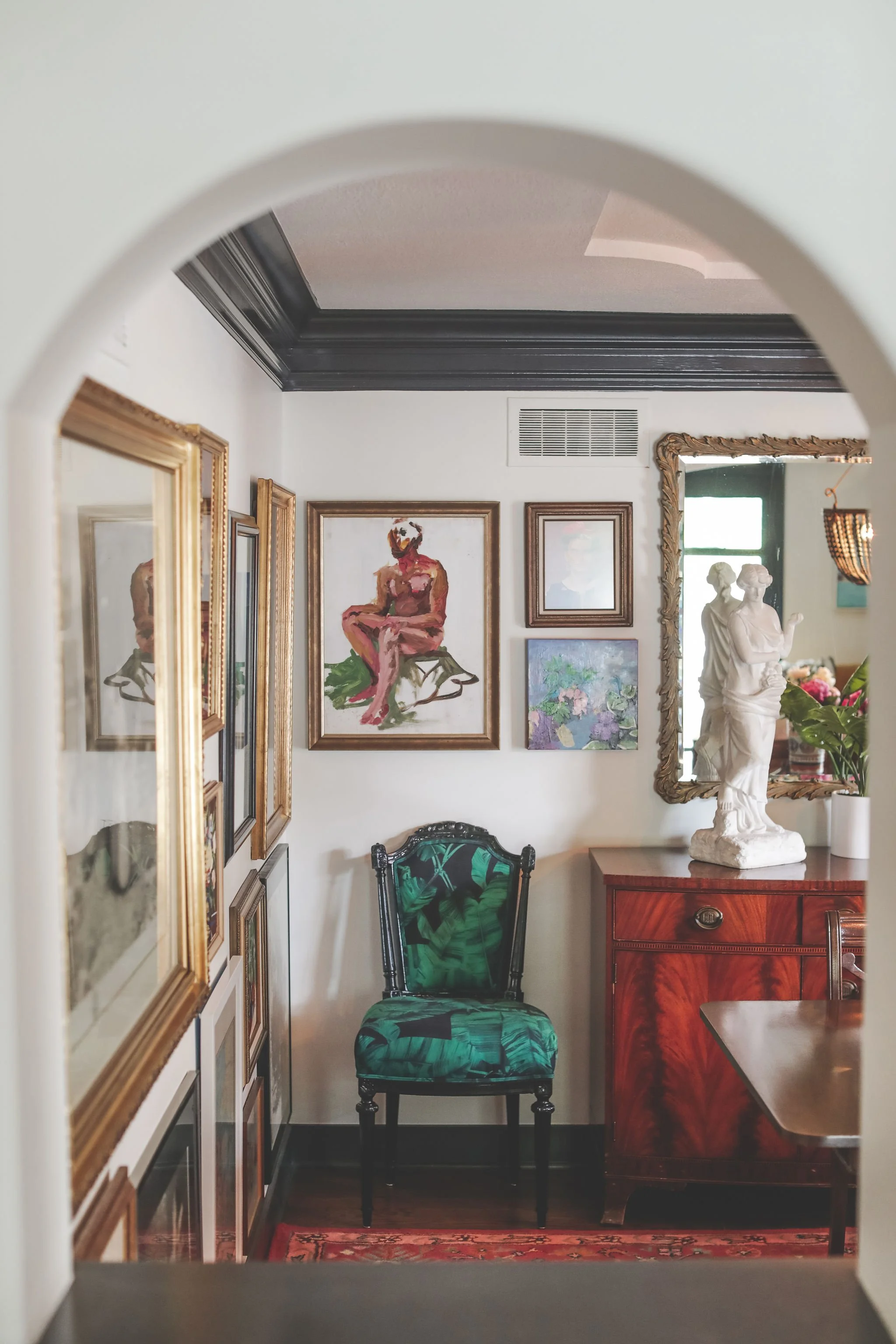 Maximalist art-filled hallway with gallery wall, vintage green and black chair, ornate gold frames, and layered eclectic styling by Melissa B. Rodgers Interiors & Styling