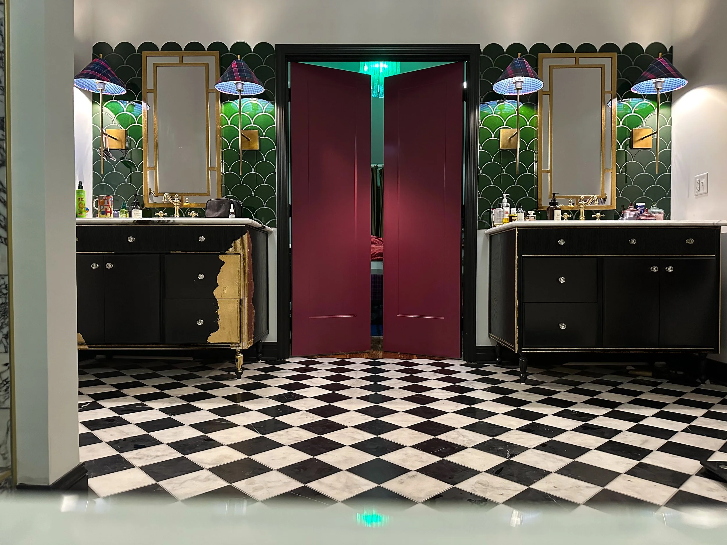 Bold Art Deco bathroom with black and white checkered floor, emerald green scalloped tile walls and deep burgundy double doors