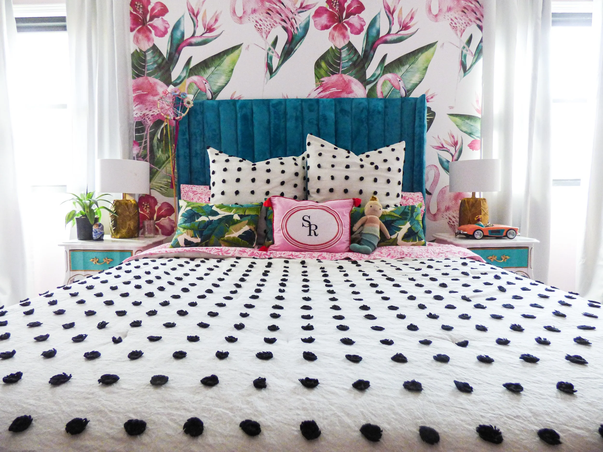 Barbie inspired maximalist bedroom with bold floral wallpaper, teal velvet custom headboard, layered pillows and black pompom bedding styled by Melissa B. Rodgers