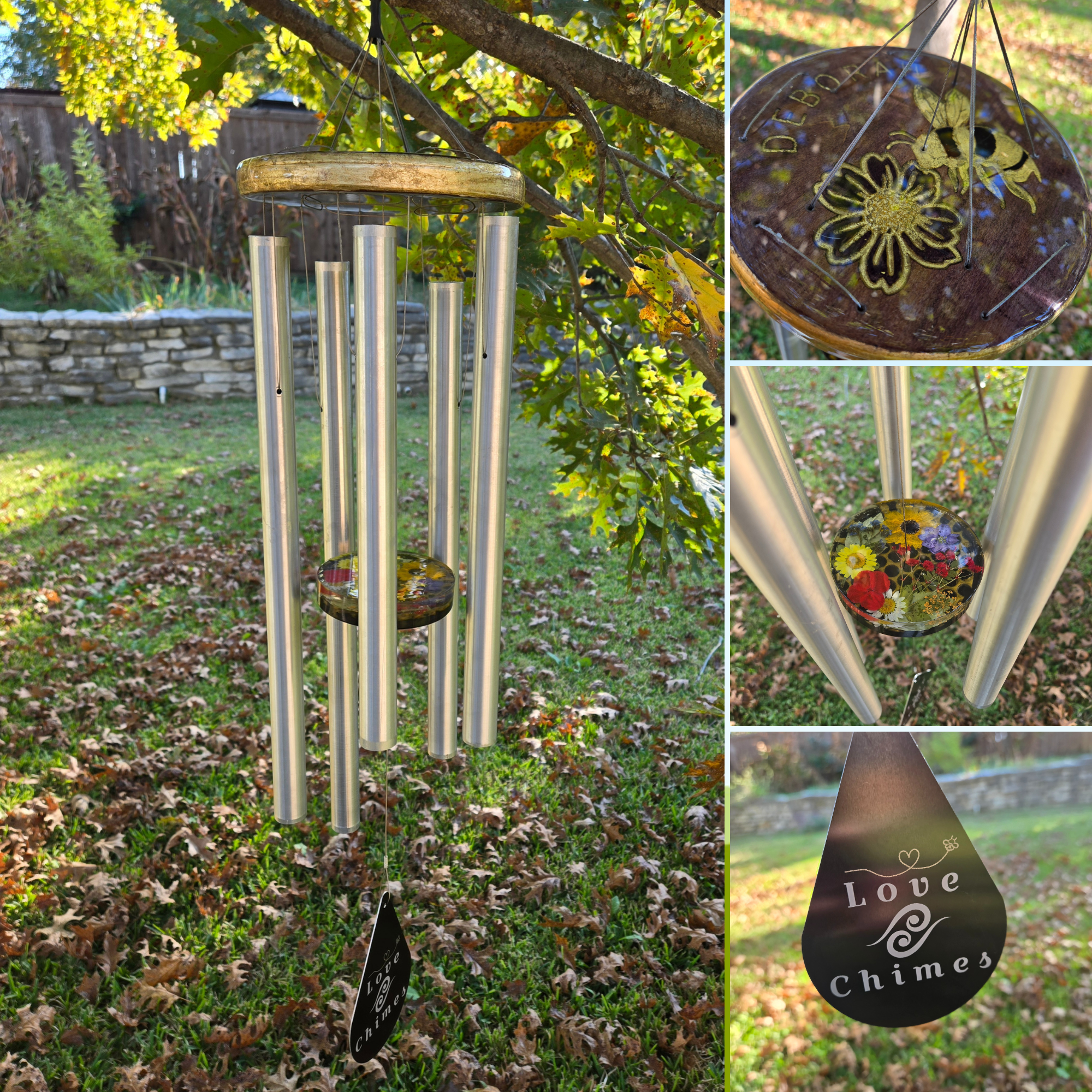 A decorative wind chime with five metal tubes hanging from a circular ceramic top decorated with a flower pattern. A black teardrop-shaped tag at the bottom reads 'Love Chimes' with a small heart and a swirl design.