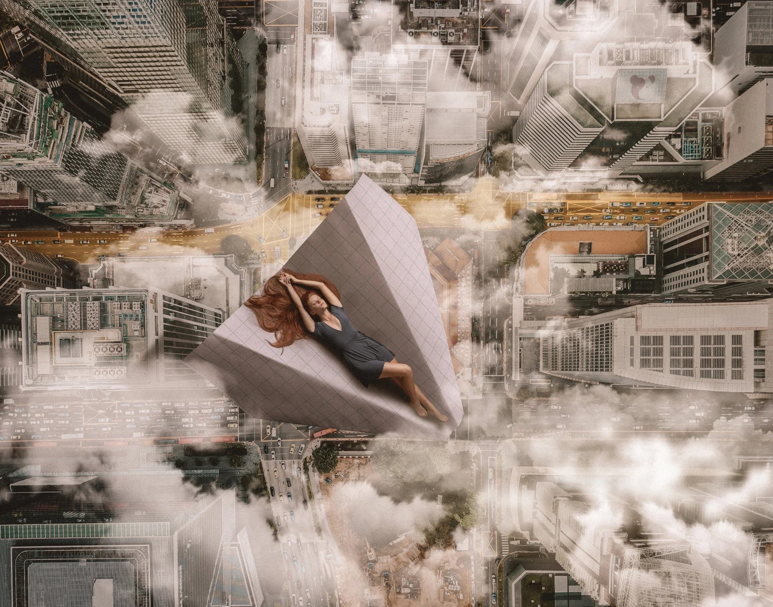 A woman in a green dress lying on a paper plane above a cityscape with clouds surrounding the buildings.