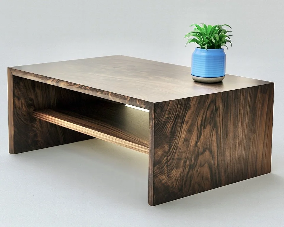 A modern wooden coffee table with a small blue pot containing a green plant on top.