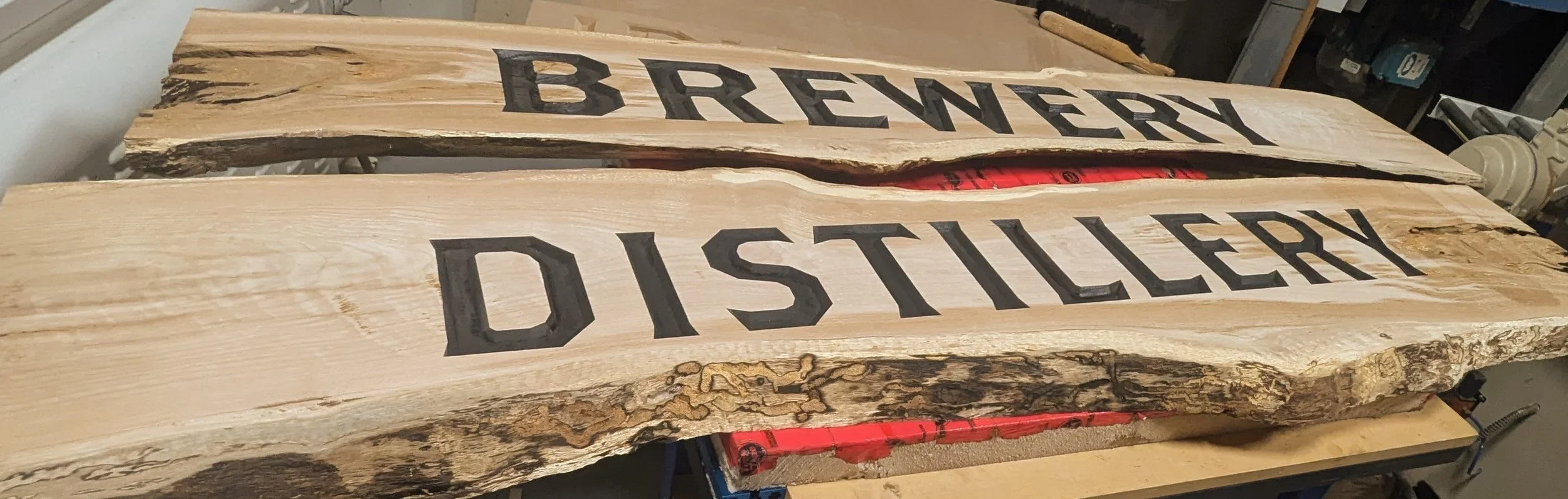 Wooden sign with the words "Brewery Distillery" painted on it in black