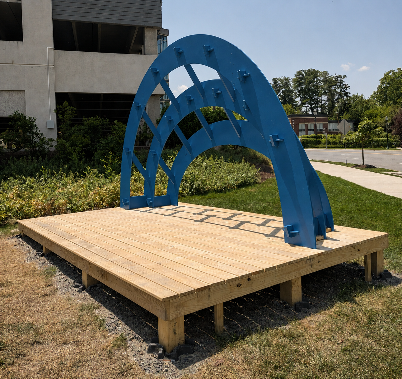 Nested blue arched bandshell sculpture on an outdoor wood platform, a public art installation