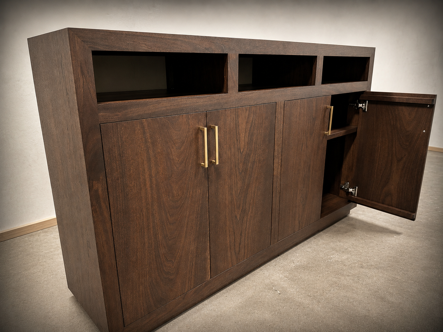 Black walnut credenza with open upper compartments and cabinet doors with brass pulls, one door open, in the workshop