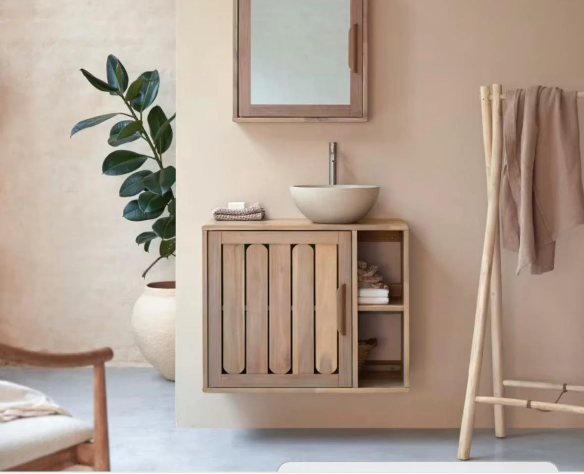 Un lavabo de cerámica en un mueble de madera con un espejo encima de la pared, en un baño con decoración minimalista y plantas verdes.