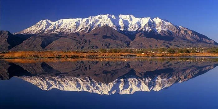 Snow-capped mountain reflected in a calm lake.