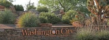Sign reading Washington City, where Dixie resides, surrounded by desert landscaping with drought-tolerant plants.
