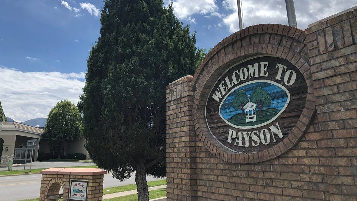 A brick sign that reads "Welcome to Payson" with an illustration of a gazebo, trees, and hills.