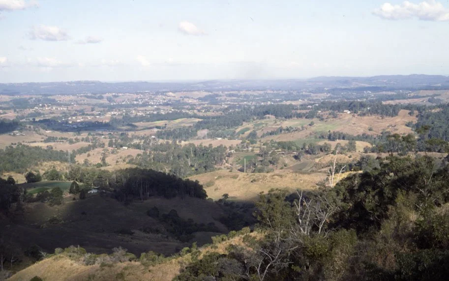 Scenic view of rolling hills and farmland under a partly cloudy sky in a rural landscape.