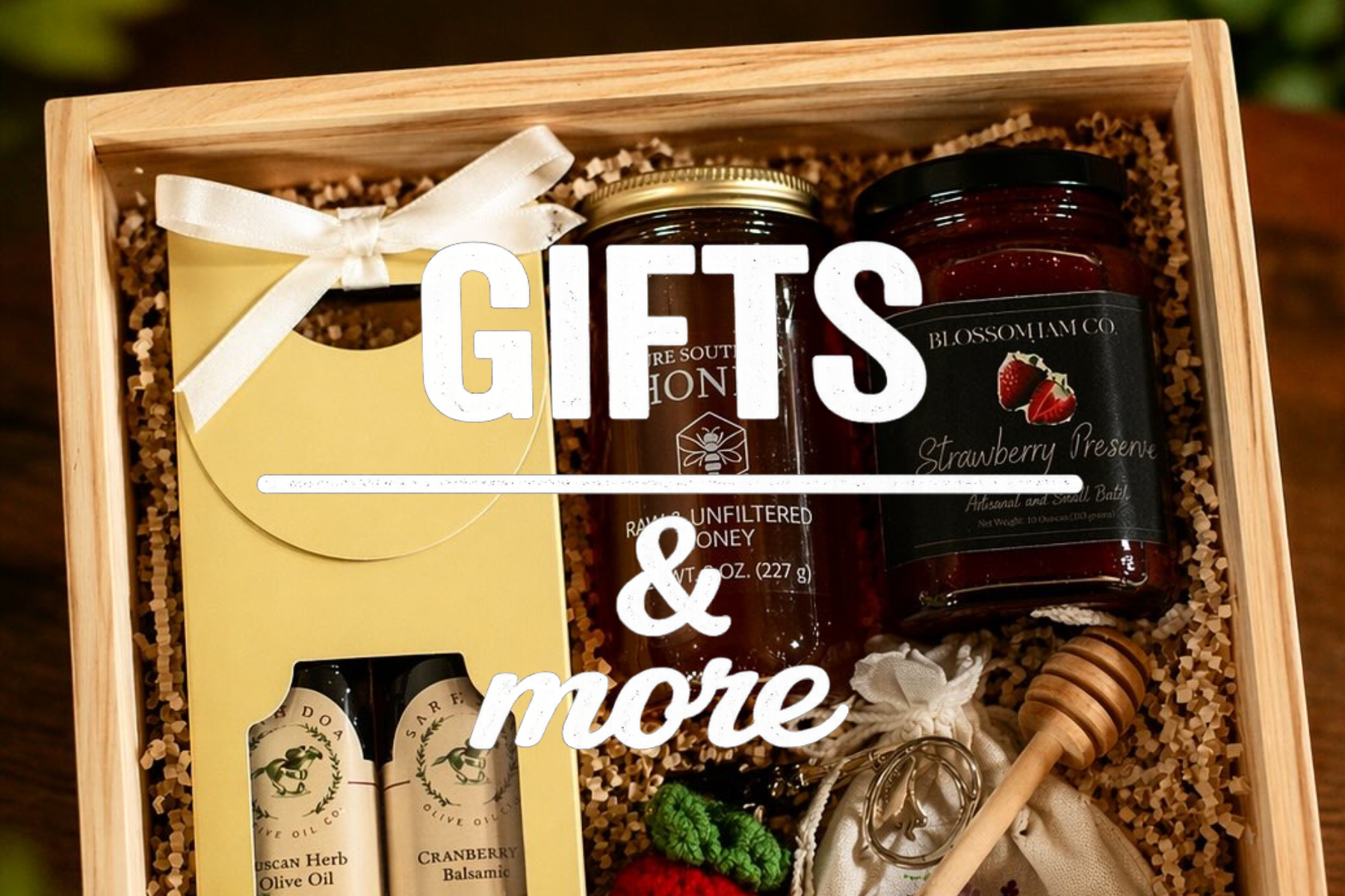 Gift box with honey, strawberry preserve, olive oils, and honey dipper, decorated with ribbons and natural filler.