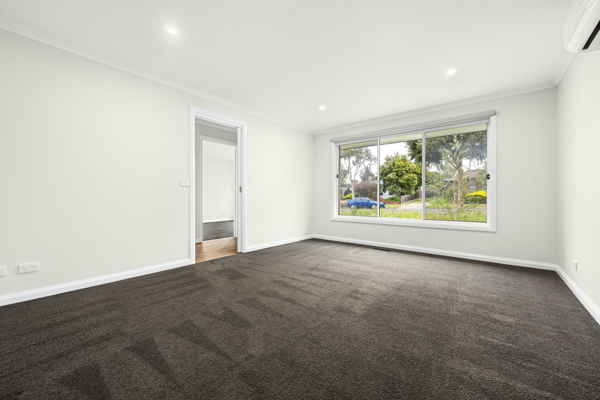 Empty living room with large window, white walls, and dark carpet that is ready for a move-in or move-out cleaning service in Columbus, Ohio.