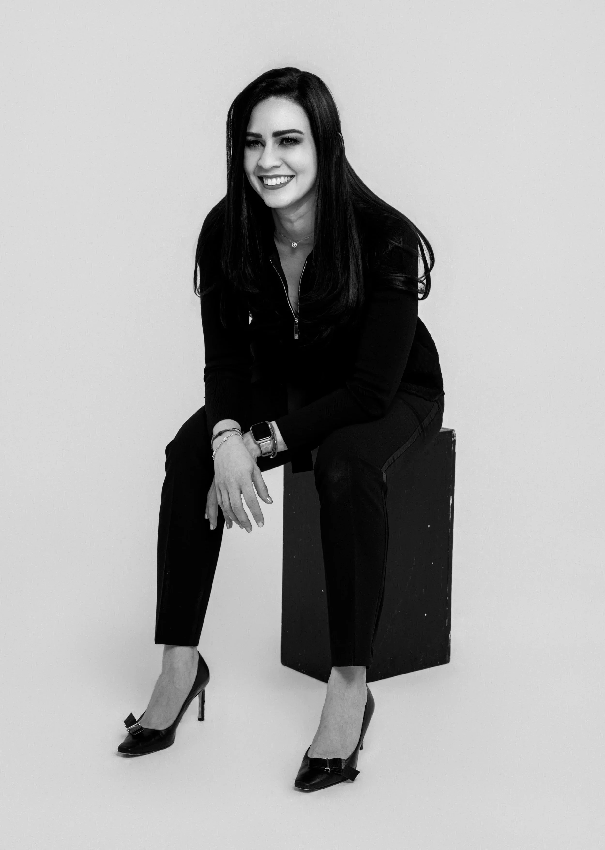 Retrato en blanco y negro de una mujer sonriente sentada en un banco negro