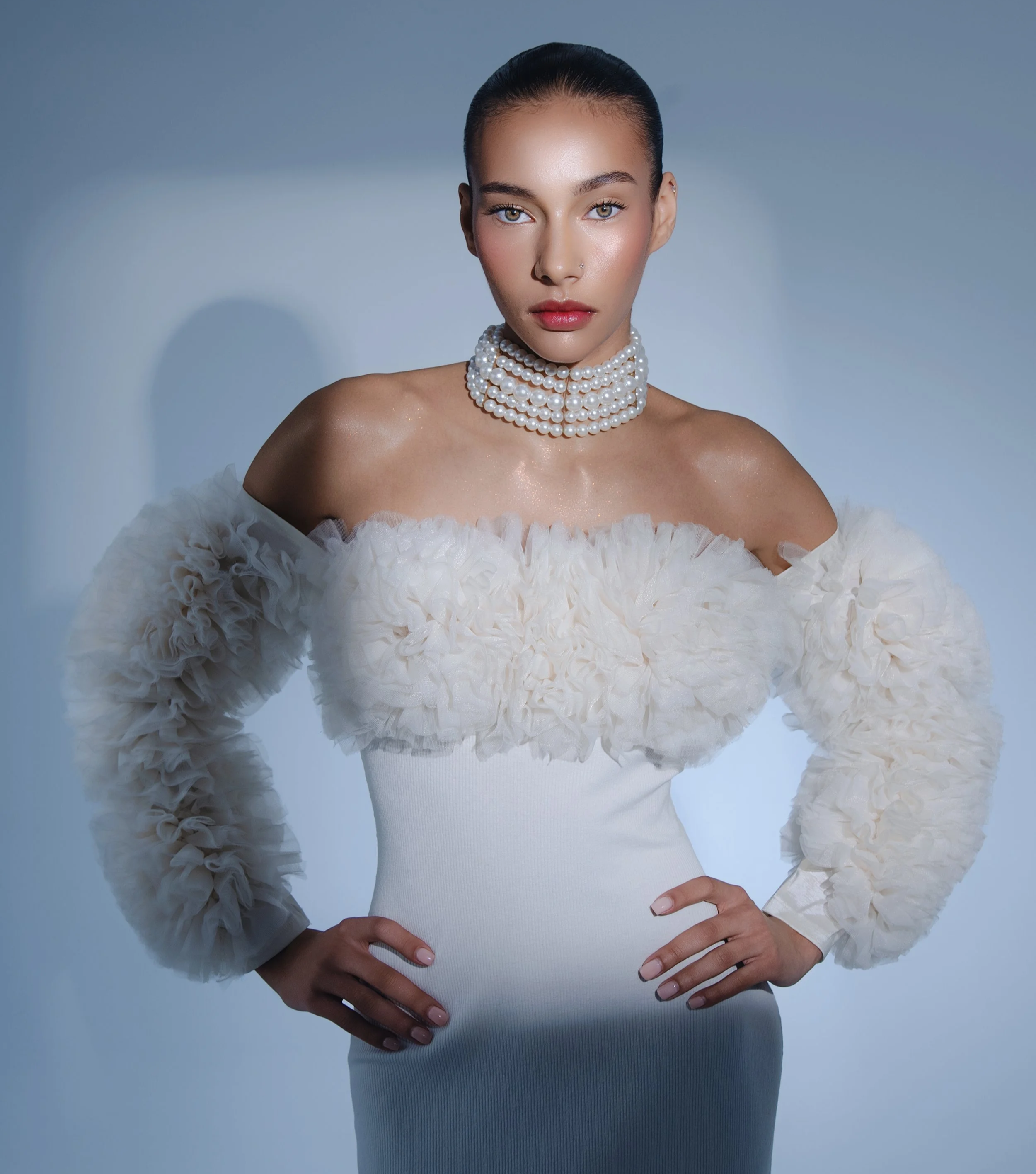 Retrato de una mujer con vestido blanco y collar de perlas sobre fondo azul claro