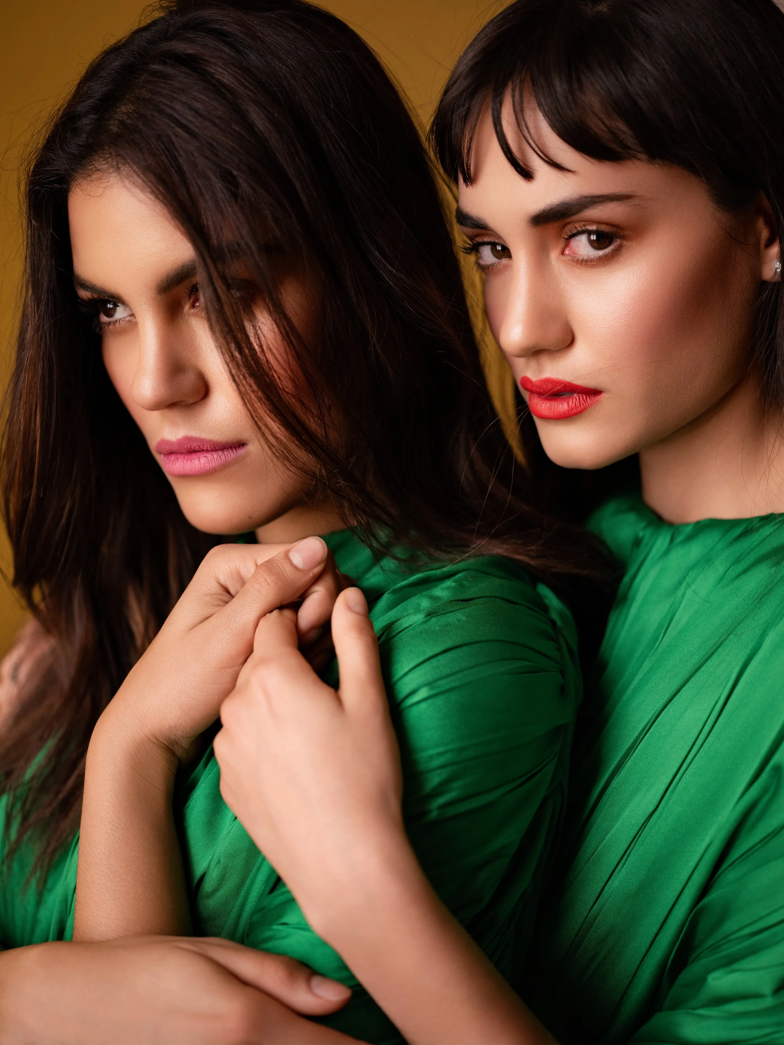 Retrato cercano de dos mujeres con vestidos verdes sobre fondo mostaza