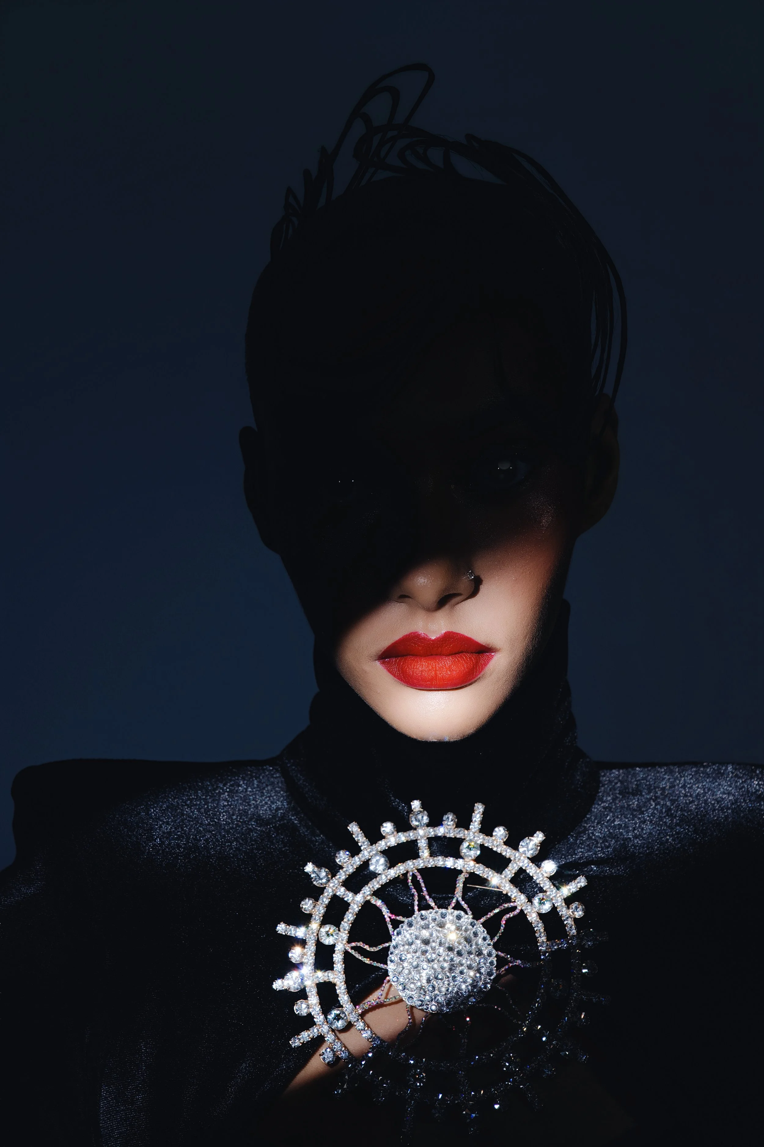 Editorial beauty portrait of a woman with her face partially covered, emphasizing red lips and graphic styling under controlled studio lighting.