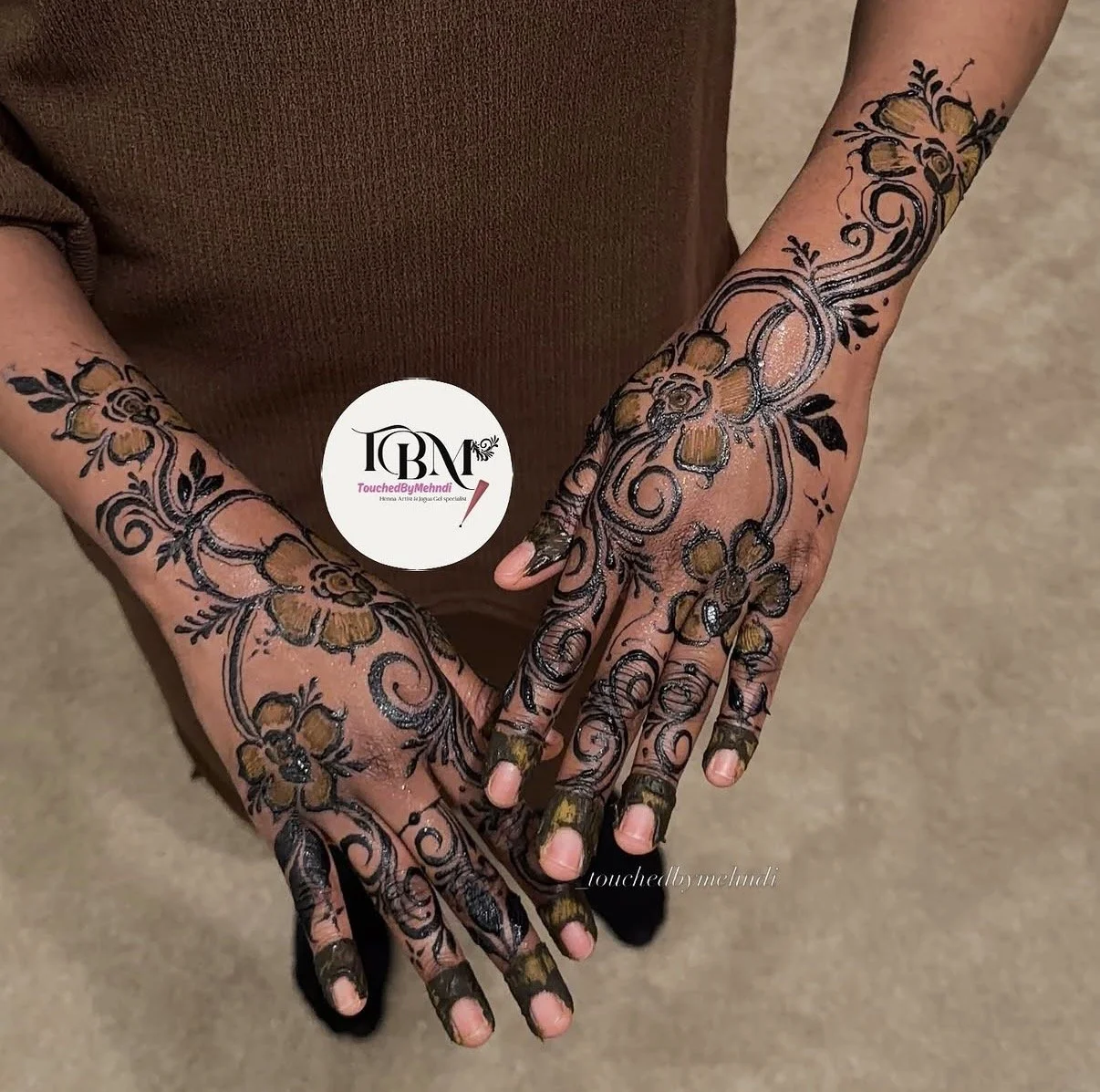 Hands with henna tattoos featuring floral and swirl designs, with some parts of the fingers covered in henna.