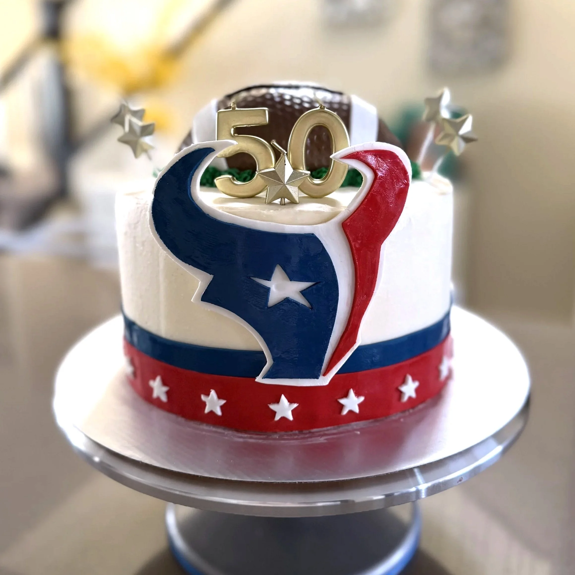 A celebratory cake with Texas-themed decorations, including a large Texas flag emblem and a golden '50' candle on top.