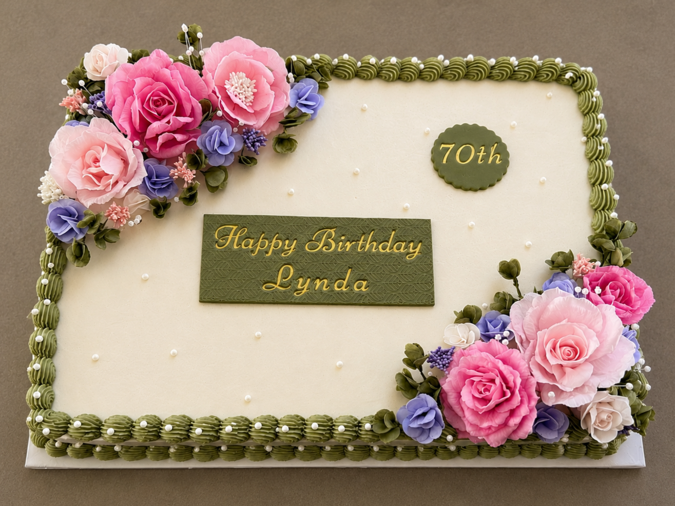 Elegant custom sheet cake featuring smooth buttercream frosting, sage green piped borders, handcrafted wafer paper flowers in soft pink and lavender tones, pearl accents, and a personalized birthday plaque. Designed by Graze & Glaze'd in Calgary for 