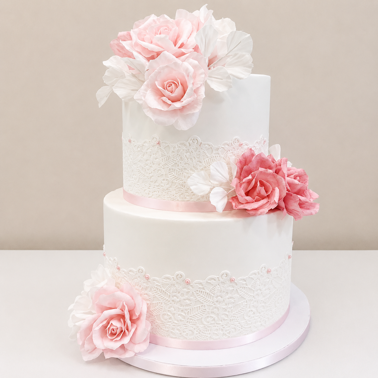 A timeless two-tier wedding cake featuring delicate lace detailing, handcrafted blush wafer paper florals, and soft romantic finishes. Designed with elegant textures and subtle pearl accents, this custom wedding cake creates a refined centerpiece per