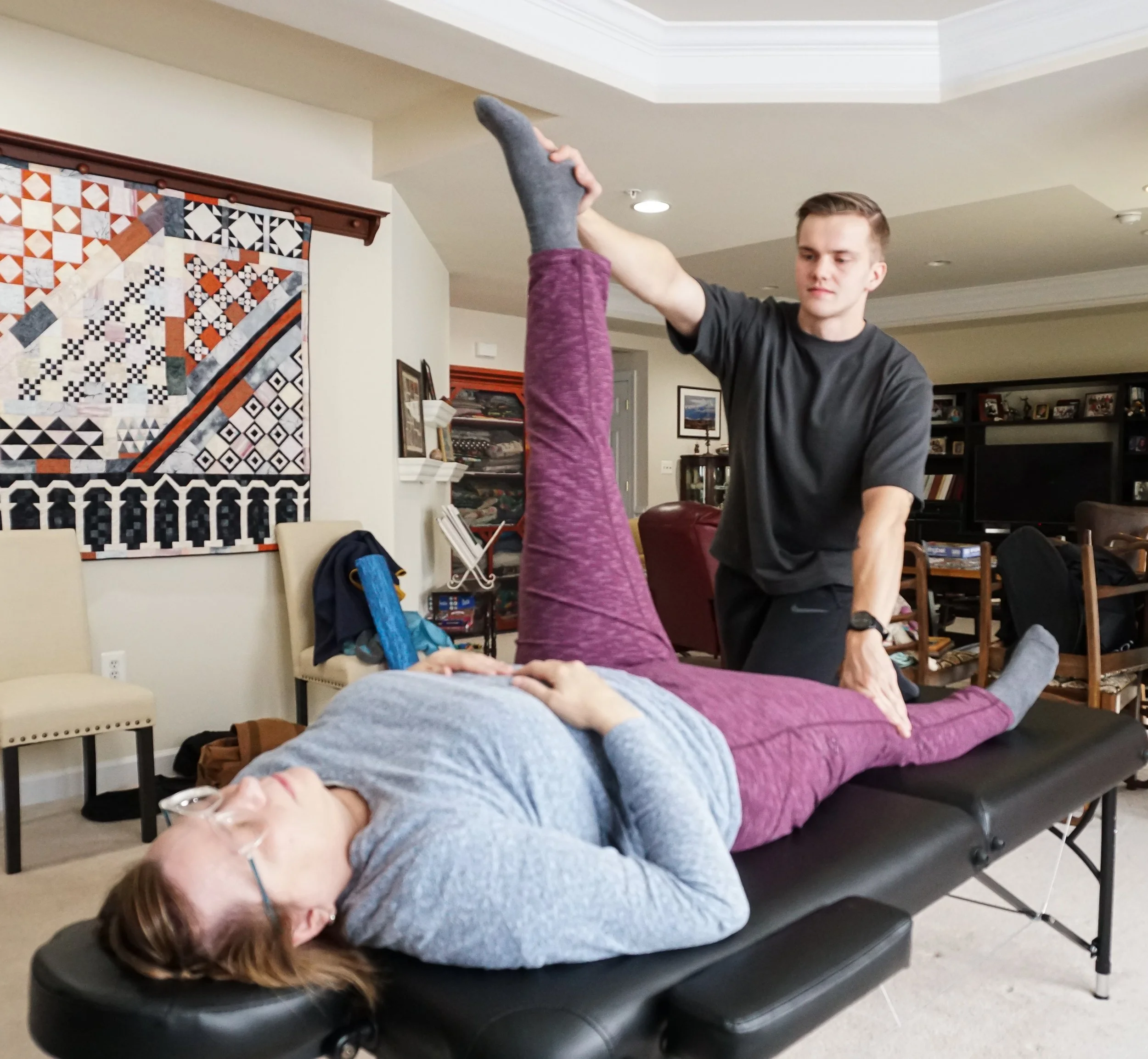 Woman receiving an assisted stretch at home with a wellness professional.