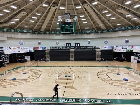 Empty basketball court inside a dome with a person walking across the floor.