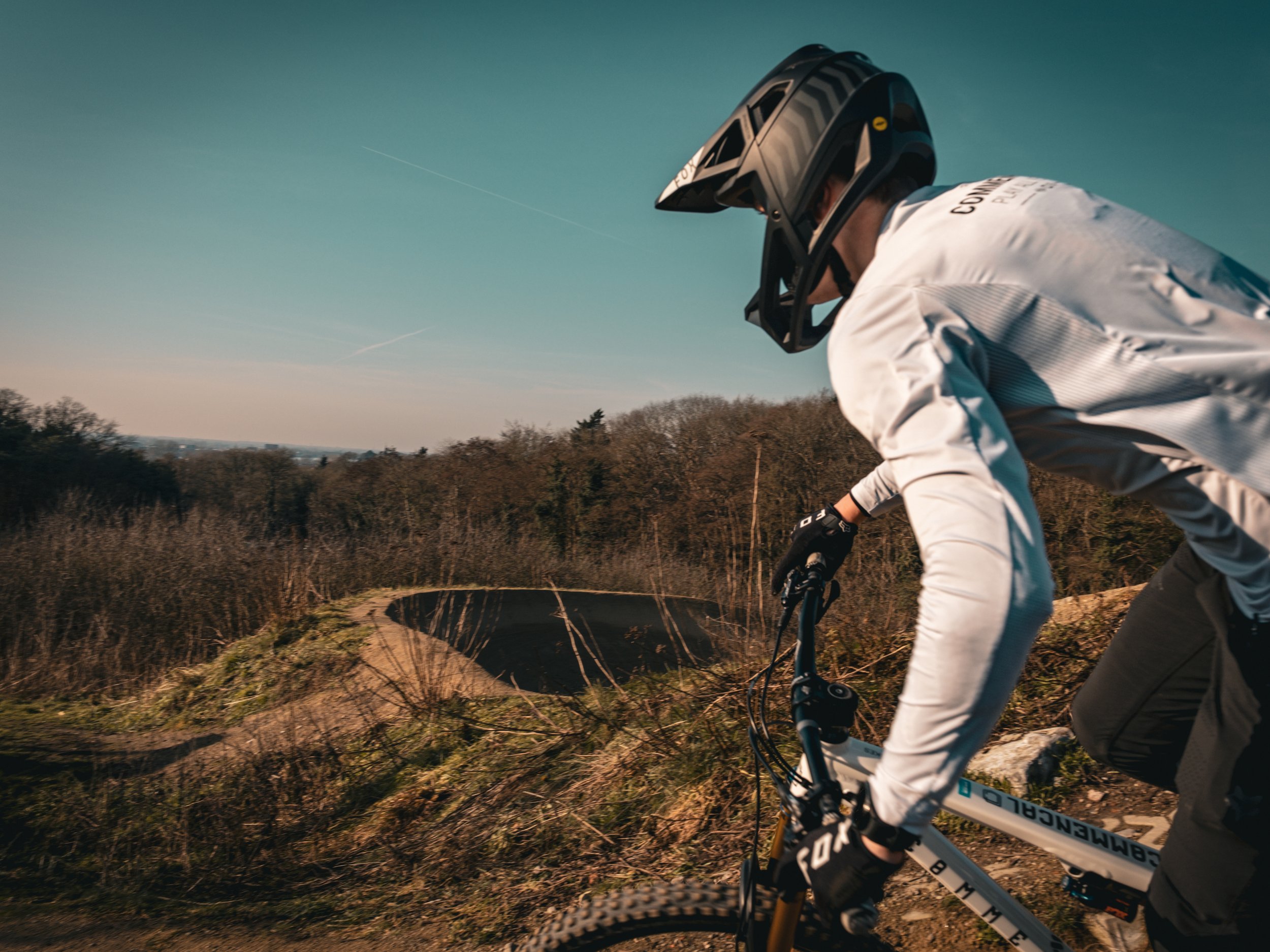 Een persoon die mountainbiked op een pad door de natuur, met een helm en mountainbike in een landelijke omgeving.