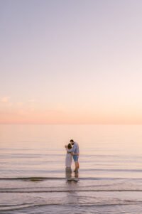 Perhekuvaus Yyterissä, kaunis auringonlasku ja pari seisomassa rantavedessä