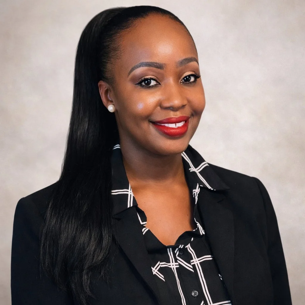 A professional woman with long black hair, wearing a black blazer and a black and white checkered shirt, smiling with red lipstick, against a neutral background.