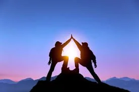 Silhouetted figures standing on a mountaintop at sunrise, symbolizing guidance, growth, and life coaching transformation.