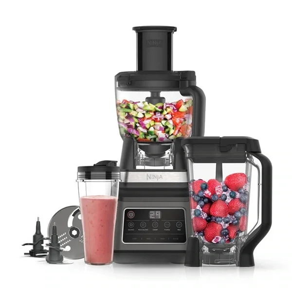 Robot da cucina Ninja con contenitori di frutta e verdura tagliata, frullato di frutta rosa e smoothie di frutta congelata.