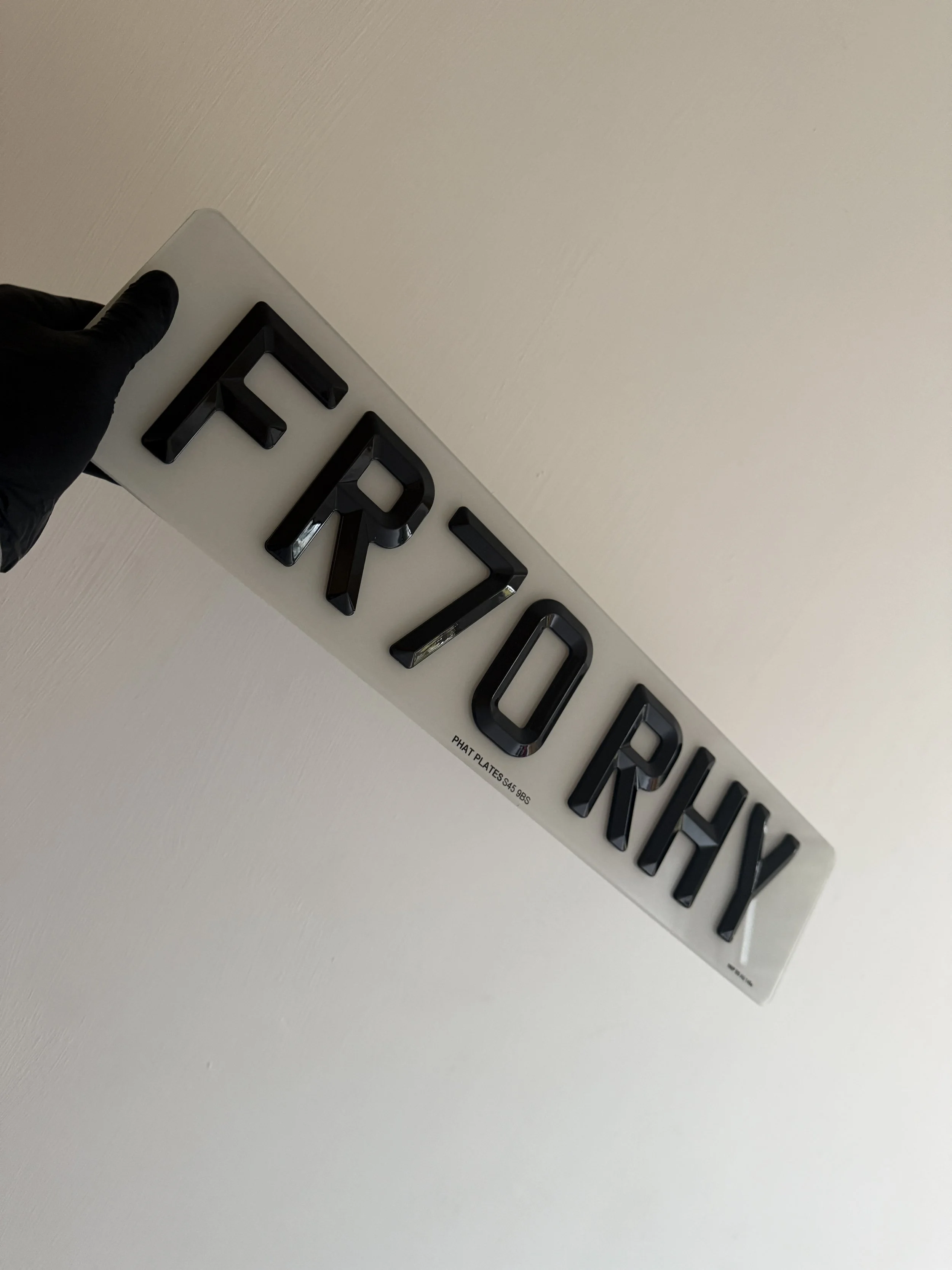 Black lettering spelling 'FERRY' on a clear background, held by a person wearing a black glove.