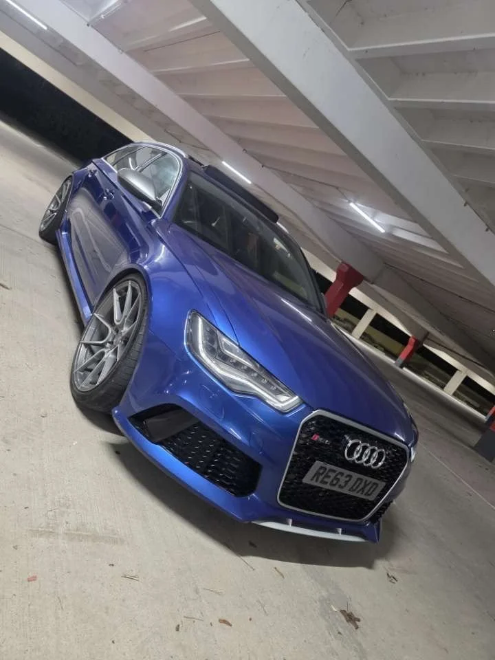 Blue Audi RS3 sedan parked in an underground parking garage.