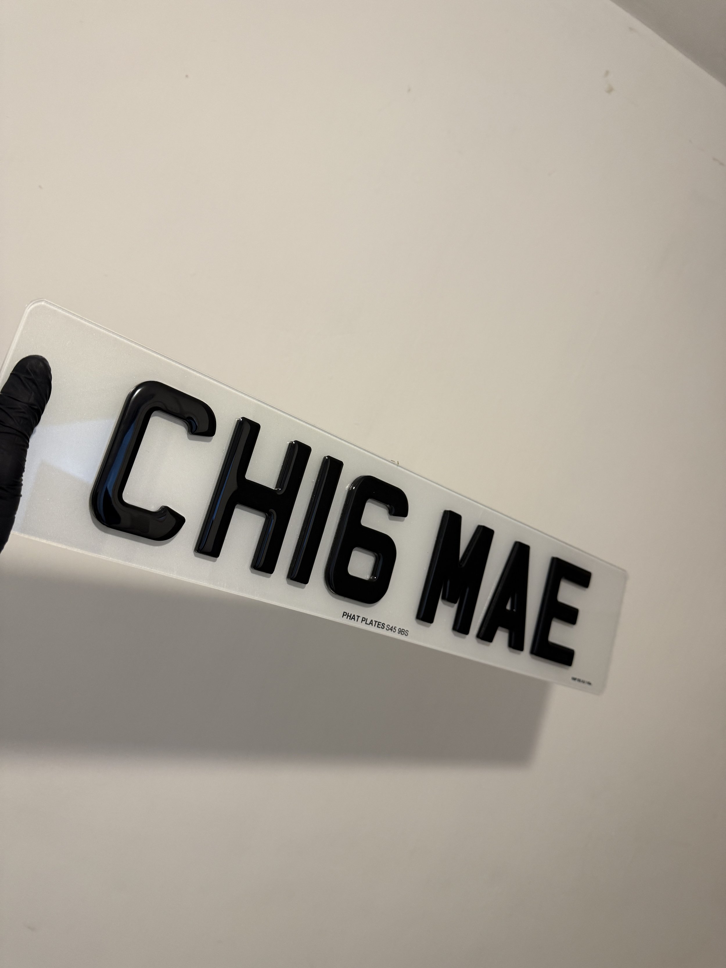 Plastic sign with black 3D letters reading 'CHIG MAE' against a plain white background.