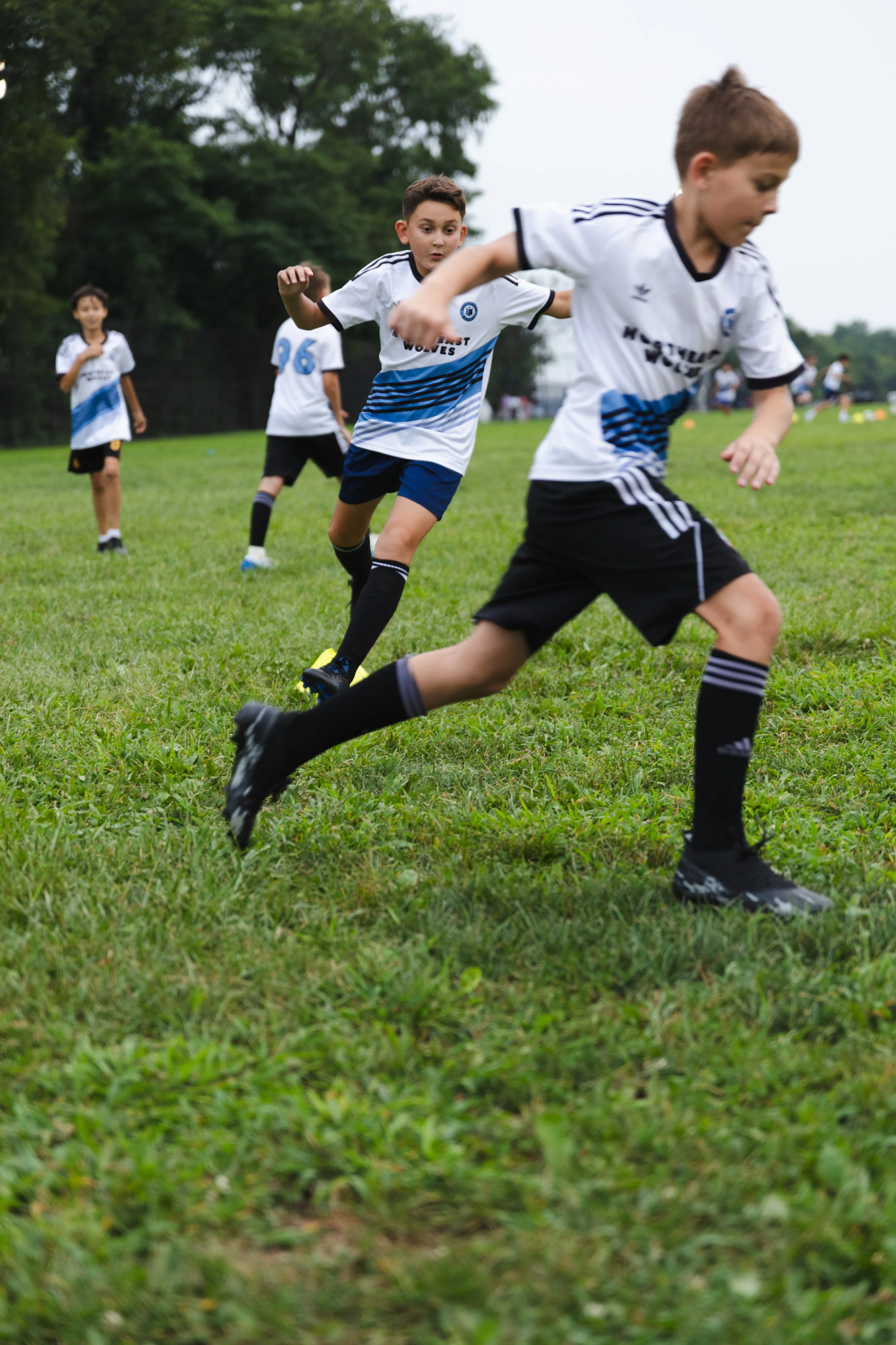 Young boys in soccer jerseys running on a grassy field during a soccer game.