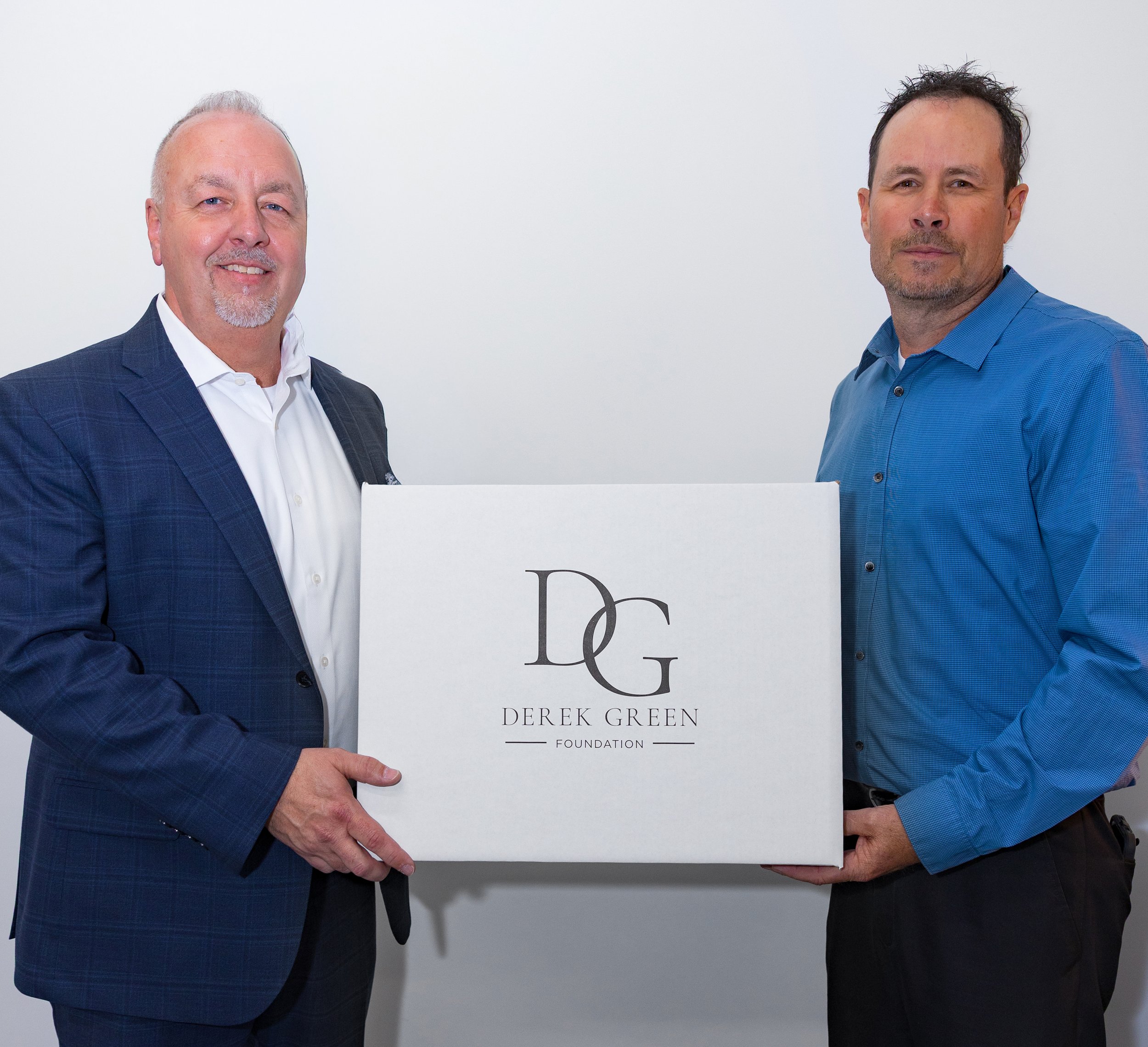 Founders holding a white box with the logo 'DG' and the text 'Derek Green Foundation' in front of a white background.